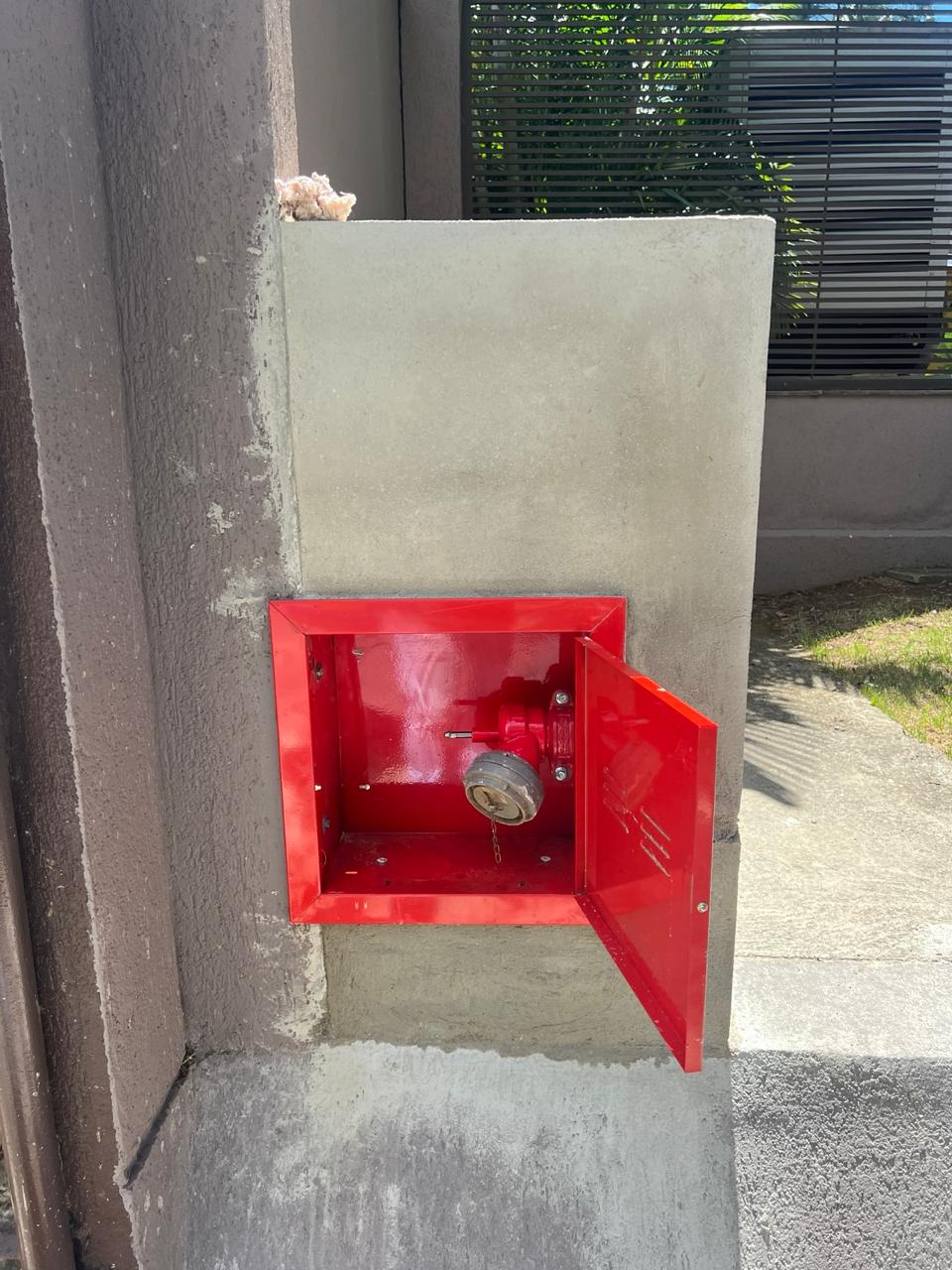 Caixa de hidrante de recalque externo vermelha instalada em muro de edificação pela Invictor