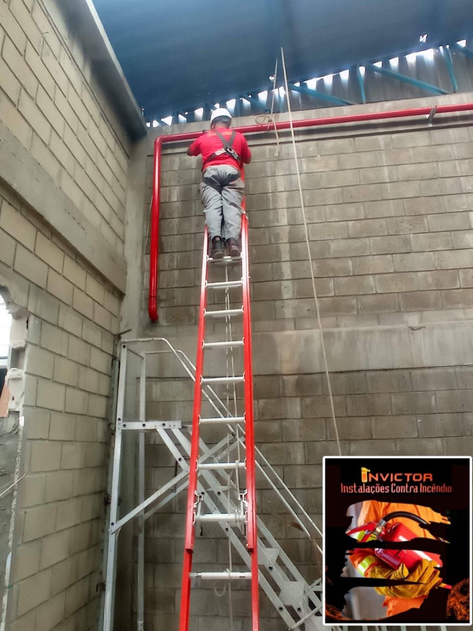 Técnico Invictor instalando tubulação vermelha em altura com EPI completo